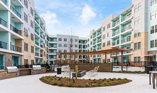a courtyard with tables and chairs and trees and buildings in the background